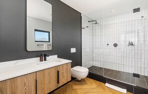 Ein modernes Badezimmer mit großem Spiegel, Waschbecken in Weiß, Toilette und Duschkabine.