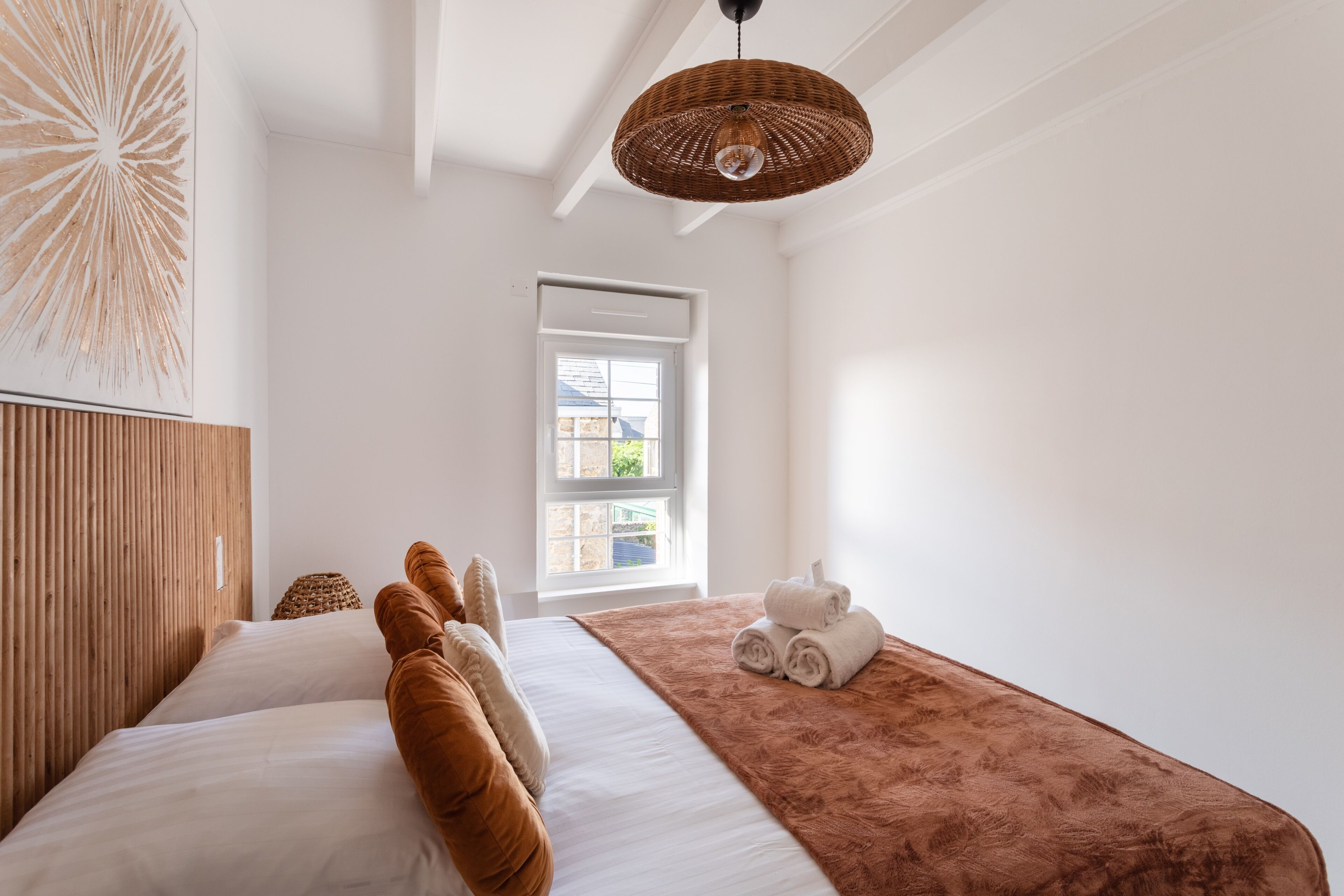 Ein Hotelzimmer mit einem Bett, einem Fenster, einer Tür und einer Pendelleuchte.