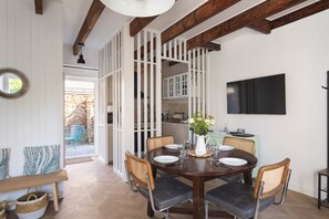 Un coin repas avec une table ronde, des chaises et un téléviseur fixé au mur.
