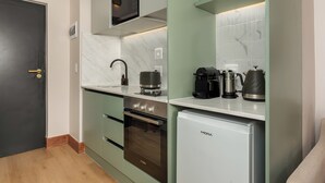 Eine kompakte Küche mit Mikrowelle, Kaffeemaschine und kleinem Kühlschrank.