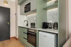 A compact kitchen with a microwave, coffee maker, and a small refrigerator. - Charlie and the Chairman | Modern CBD Retreat (Cape Town)