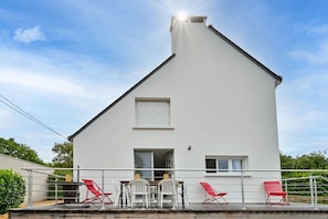Ein weißes, zweistöckiges Gebäude mit Balkon, kleinem Fenster und einer Tür.