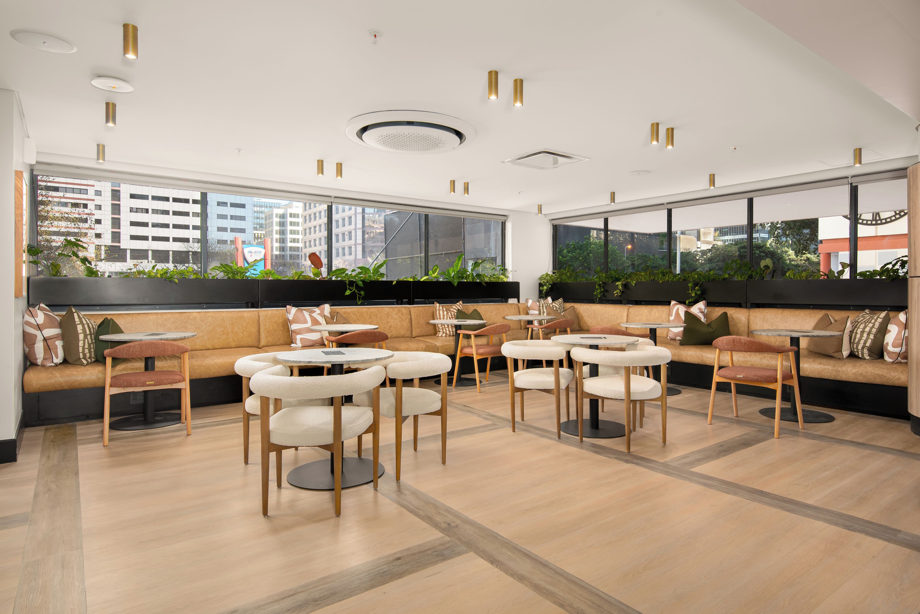 Un espace détente moderne avec des canapés, des tables rondes et des plantes en pot.
