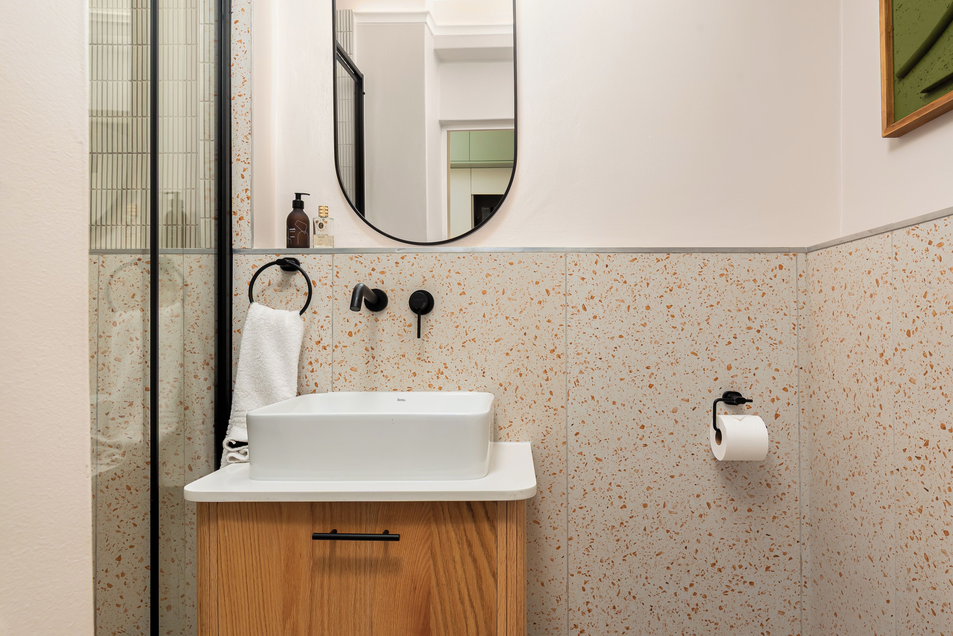 A bathroom with a white sink, a wooden cabinet, a mirror, and a toilet paper holder.