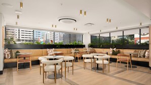 Un moderno espacio lounge con sofás, mesas redondas y plantas en macetas.