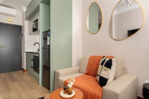 A modern living room with a sofa, a small table with a vase, and two wall-mounted mirrors. - Charlie and the Chairman | Designer CBD Apartment (Cape Town)