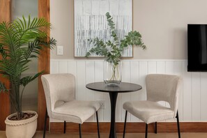 A room with two chairs, a table, a potted plant, and a wall-mounted TV. - Charlie and the Chairman | Modern CBD Apartment (Cape Town)
