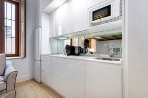 A modern kitchen with white cabinetry, a built-in microwave, a coffee maker, and a sink. - Genteel Home Antonio Marchena 001 (Seville)