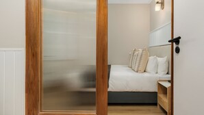 A bedroom with a bed, bedside table, and a wooden wardrobe. - Charlie and the Chairman | Contemporary Stay (Cape Town)