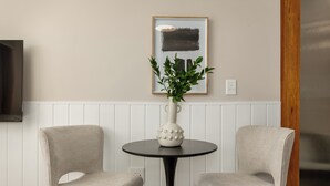 A room with two chairs, a table, a potted plant, and a framed picture on the wall. - Charlie and the Chairman | Contemporary Stay (Cape Town)