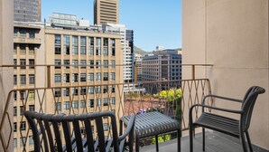 Uma varanda com duas cadeiras, com vista para um horizonte urbano repleto de edifícios modernos, incluindo um com o nome 'Luno' no topo.