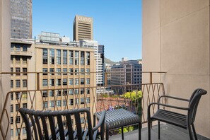 A balcony with two chairs, overlooking a cityscape with modern buildings, including one with the name 'Luno' on top. - Charlie and the Chairman | Designer Escape (Cape Town)