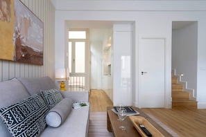 A modern living room with a sofa, coffee table, and a staircase leading to another level. - Genteel Home Antonio Marchena 202 (Seville)