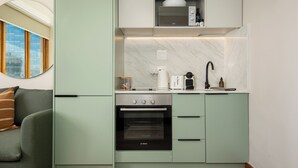 Eine kompakte Küche mit Backofen von Bosch, einer Mikrowelle und einer Kaffeemaschine.