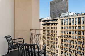 A balcony with two chairs, a view of a tall building, and a clear sky. - Charlie and the Chairman | CBD Suite with Balcony (Cape Town)
