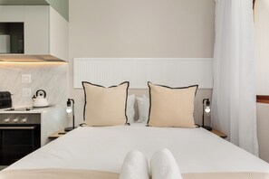 Et hotelværelse med seng, sengeborde, elkedel og et moderne tekøkken.