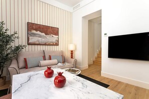 A modern living room with a sofa, a flat-screen TV, a coffee table with decorative items, and a potted plant. - Genteel Home Antonio Marchena 201 (Seville)
