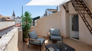 Eine Dachterrasse mit zwei Stühlen, einem Tisch und einem Blumentopf.