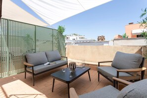 A patio with a sofa, chairs, and a table, featuring a view of buildings and a clear sky. - Genteel Home Antonio Marchena 201 (Seville)