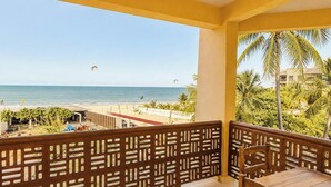 A balcony with a view of the beach and ocean, featuring a wooden railing and a table. - Pousada Sunrise Beach (Caucaia)