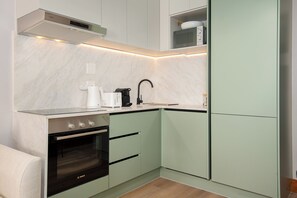 A compact kitchen with a Bosch oven, a microwave, and a coffee maker on the countertop. - Charlie and the Chairman | Modern CBD Apartment (Cape Town)