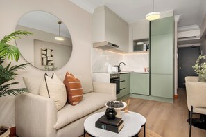 A modern living room with a sofa, a round coffee table, and a dining area with a chair. - Charlie and the Chairman | Modern CBD Apartment (Cape Town)
