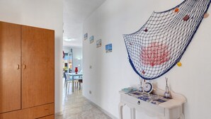 Ein Flur mit einem Holzschrank, einer weißen Wand mit einer Ziernetzstruktur und einem kleinen Tisch mit einer Uhr und Dekorationsgegenständen.