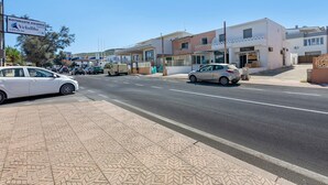 Eine Straße mit parkenden Autos, einem Schild für eine Pizzeria und Häusern mit Balkonen.
