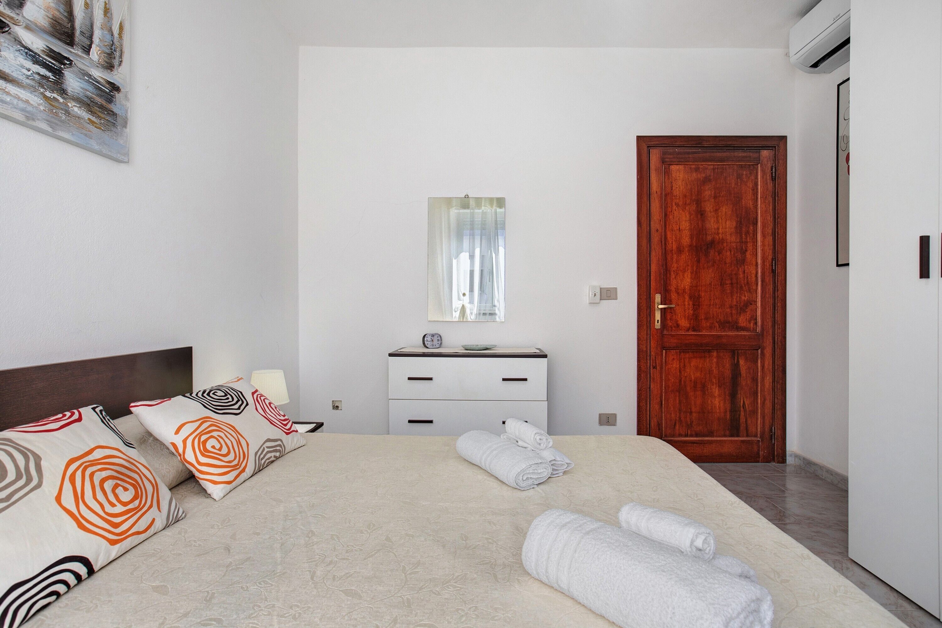 Une chambre d’hôtel avec un lit, une commode, une porte en bois et un miroir.