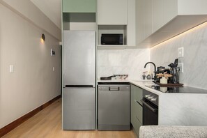 A modern kitchen with stainless steel appliances, a dishwasher, and a microwave. - Charlie and the Chairman | Sleek Studio Stay (Cape Town)