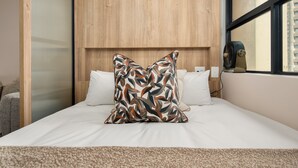 A hotel room with a bed, a window with a view, and a wooden headboard. - Charlie and the Chairman | Sleek Studio Stay (Cape Town)