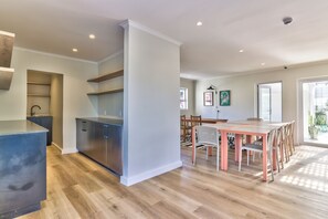 Eine moderne Küche mit integrierten Geräten, ein Essbereich mit Tisch und Stühlen sowie ein großes Fenster für natürliches Licht.