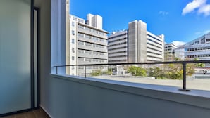 Un balcón con barandilla de metal que ofrece vistas a un paisaje urbano con edificios modernos.