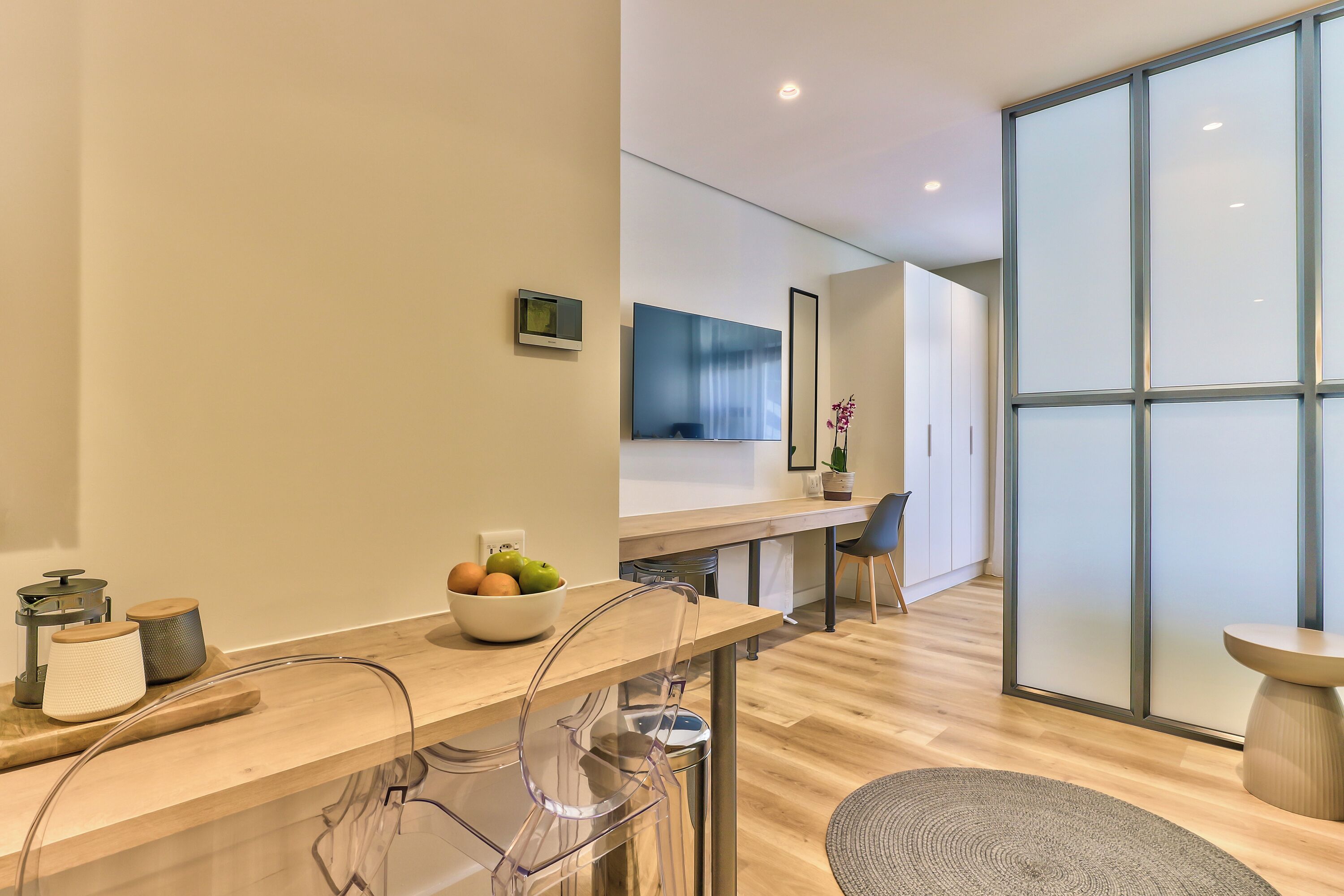 A modern kitchen with a wooden countertop, a bowl of fruit, and a coffee machine.