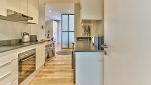 Una cocina moderna con electrodomésticos de acero inoxidable, un comedor con una mesa redonda y un ventanal que proporciona luz natural.