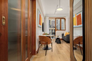 A modern interior with a dining area, sofas, and a view of the cityscape through large windows. - Charlie and the Chairman |Cityscape Stay and Balcony (Cape Town)