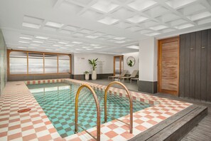 Un área de piscina con baldosas de piso a cuadros, una terraza de madera e iluminación empotrada en el techo.