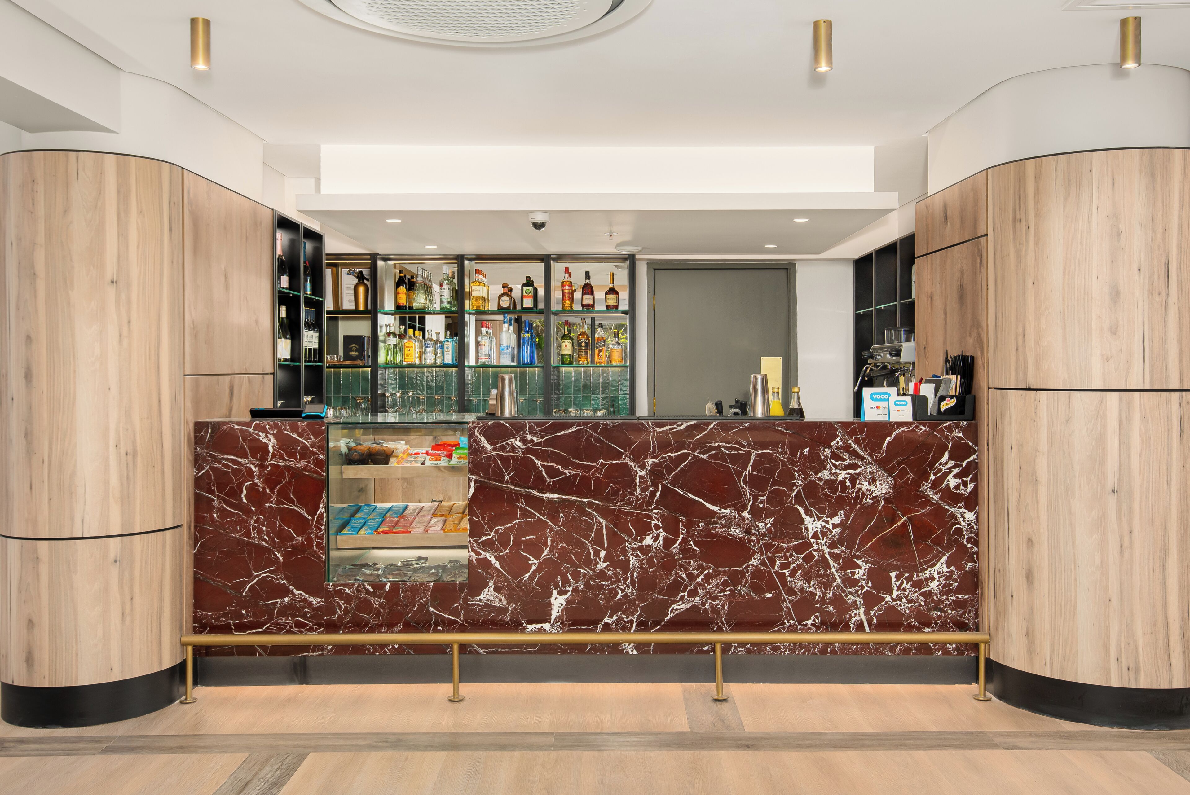 Eine moderne Bar mit Marmorplatten, Regalen voller Spirituosenflaschen und einer Glasvitrine.