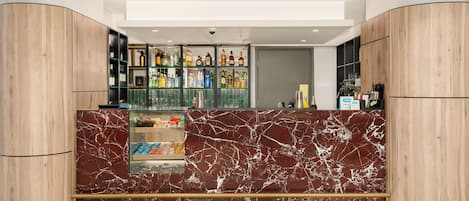 A modern bar area with marble countertops, shelves of liquor bottles, and a glass display case.