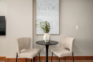 A room with two chairs, a round table, and a large abstract painting on the wall. - Charlie and the Chairman | Refined Urban Living (Cape Town)