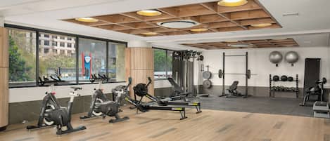 A gym with exercise equipment, large windows, and a view of the outside.
