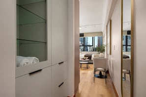 Un intérieur moderne comprenant un dressing, un coin salon avec une table et des chaises, et une grande fenêtre donnant sur la ville.