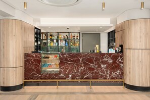 Een moderne bar met marmeren aanrecht, flessenkasten vol drank en een glazen vitrine.