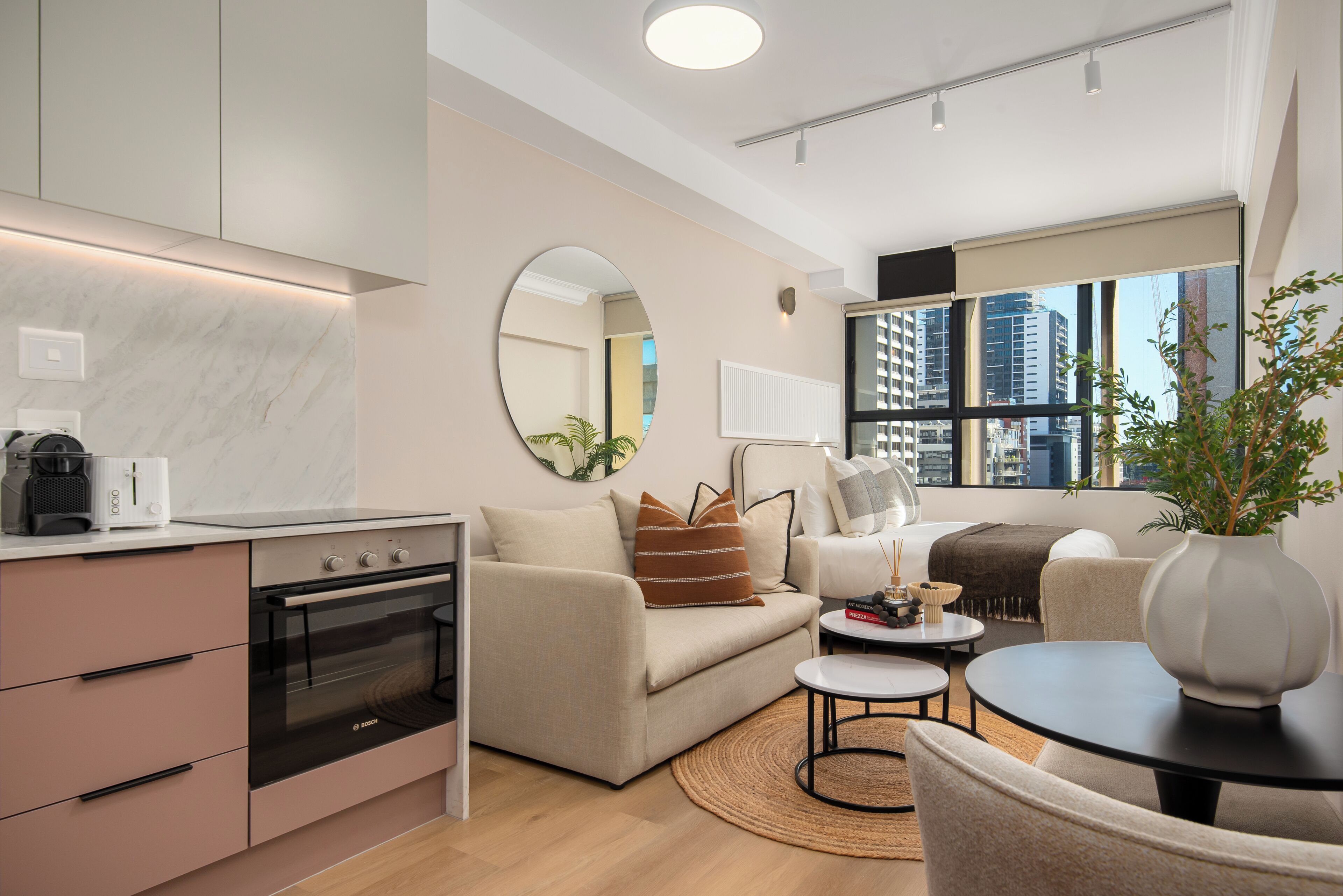 Uma sala de estar moderna com sofá, mesa de centro e vista da cidade através de amplas janelas.