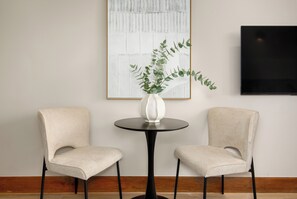 Una habitación con dos sillas, una mesa redonda y un florero con una planta.