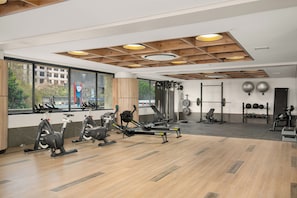 A gym with exercise equipment, large windows, and a view of the outside. - Charlie and the Chairman | Modern CBD Apartment (Cape Town)