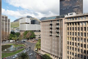 A cityscape with modern buildings, a roundabout, and a mountain in the background. - Charlie and the Chairman | Modern CBD Apartment (Cape Town)