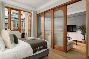 Ein modernes Hotelzimmer mit einem großen Bett, einem Fernseher, einer Couch und Blick auf die Stadt.