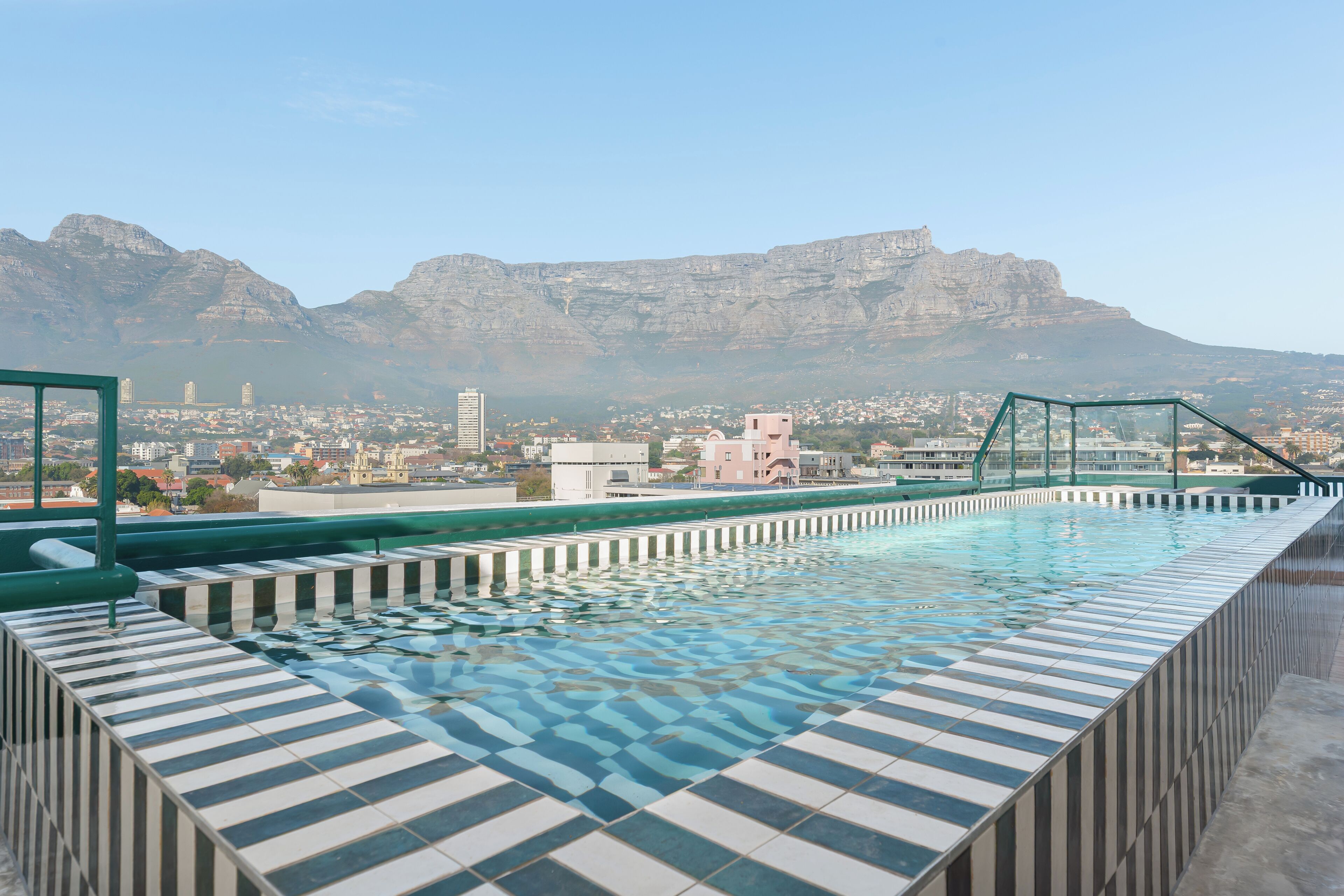 A rooftop swimming pool with a view of a city and mountains.