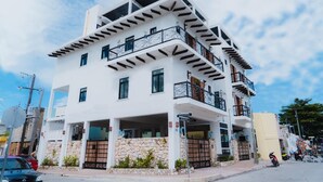 A multi-story building with balconies, a stone facade, and a clear sky. - Cozy 1-bedroom studio in perfect Isla Mujeres with AC (Isla Mujeres)